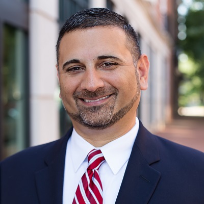 Tad Thomas in a dark suit with red striped tie