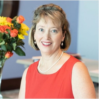 Woman in red dress with shoulder length hair and pearl earrings