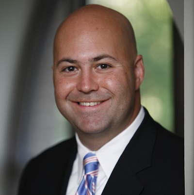 Chris Nace in black suit with pink and blue tie